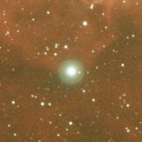 A bright star in an emission nebula, surrounded by a green reflection halo